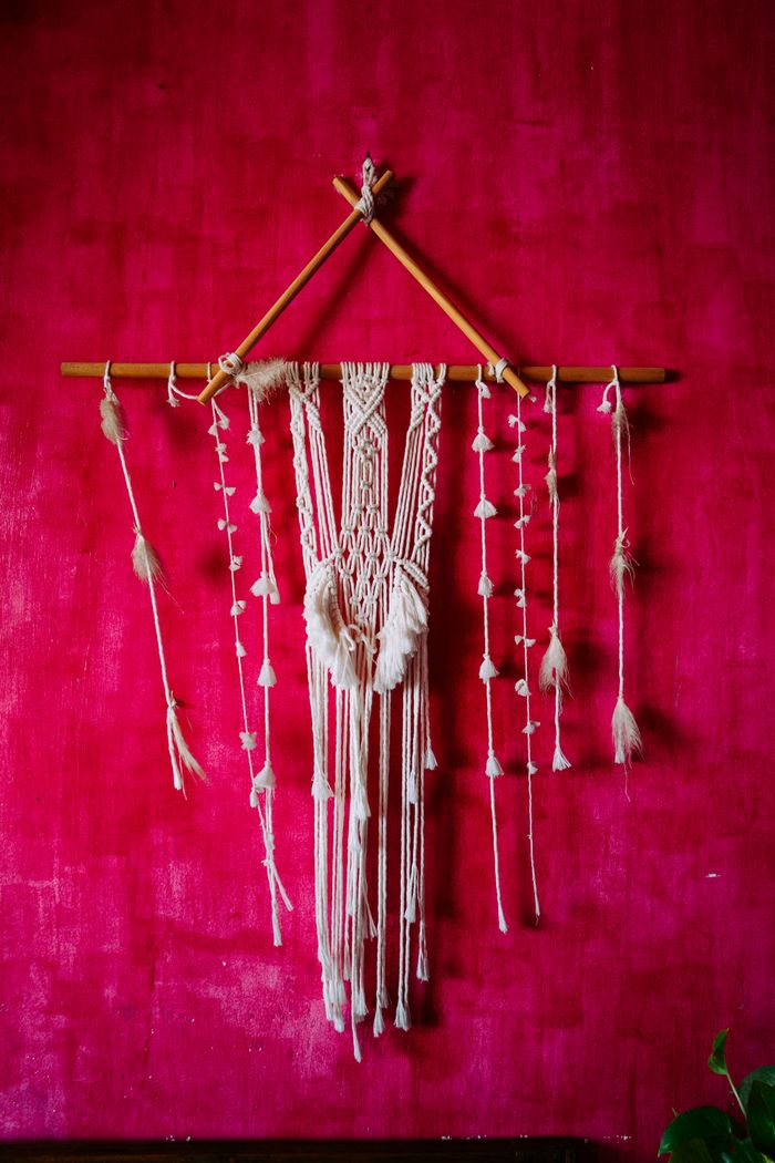 Macramé wall hanging with intricate design on a vibrant red wall, adding a bohemian touch.