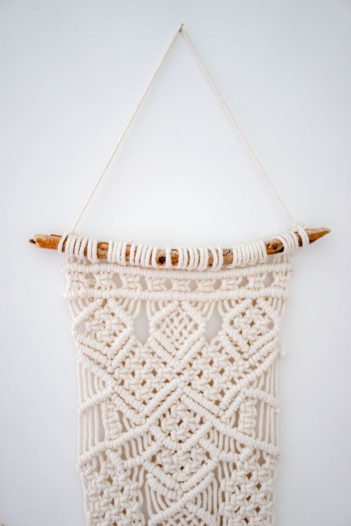 Elegant macrame wall hanging made from woven white threads for home decor.