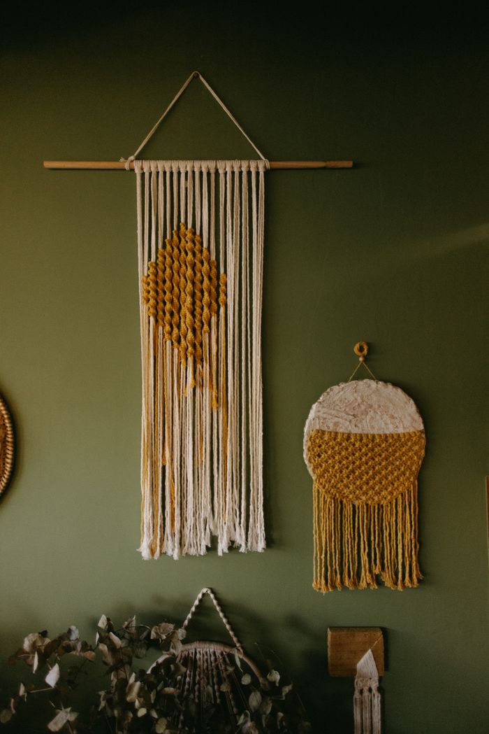 Elegant macrame wall hangings in a bohemian styled interior against a green wall.