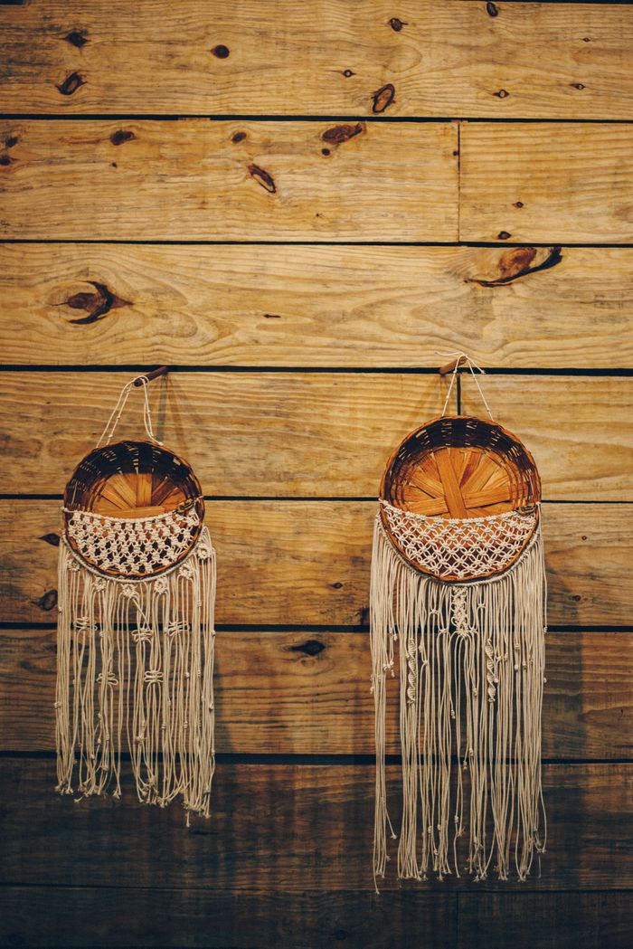 Two woven baskets with tassels hanging on a rustic wooden wall. Perfect bohemian decor.
