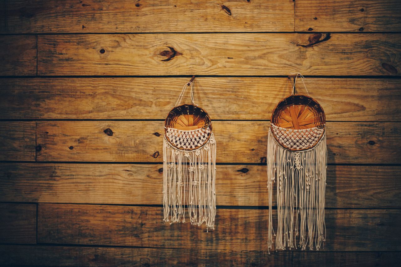 Two woven baskets with fringe hang on a rustic wooden wall, adding a handmade touch.